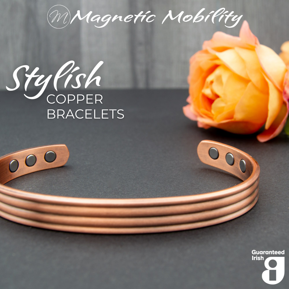 
                  
                    Load image into Gallery viewer, Front view of the Heath Copper bracelet from Magnetic Mobility. The bracelet features a simple design. Featured on a dark surface with a rose in the background signifying its popularity among gardeners for helping with aches and pains. 
                  
                