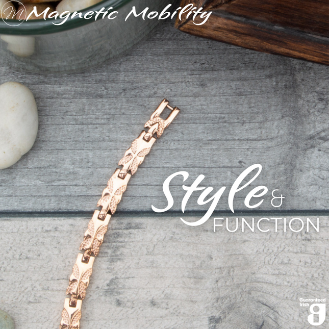Top view of the Meadowsweet Dawn 4in1 Magnetic bracelet from Magentic Mobility featuring a butterfly design on rose gold stainless steel. The bracelet is shown on a wooden surface.