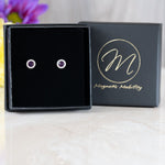 Birthstone Stud Earrings by Magnetic Mobility with purple Swarovski crystals, presented in an elegant black box. These magnetic back earrings offer fashionable pain relief and are showcased with Magnetic Mobility branding.