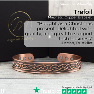 
                  
                    Load image into Gallery viewer, 45 degree view of the Trefoil Copper bracelet from Magnetic Mobility. A copper bracelet with a celtic design. The bracelet is shown on a wooden surface with a black gift box behind it. Perfect for people with arthritis and back pain. 99% pure copper. Customer review written on the image from Trustpilot stating &amp;quot;Bought as a Christmas present. Delighted with the quality and great to support an Irish business&amp;quot;. 
                  
                